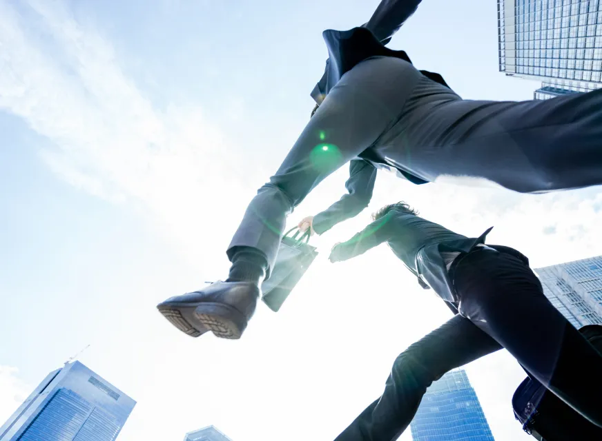 大都会で青空に向かってジャンプする2人のビジネスマン